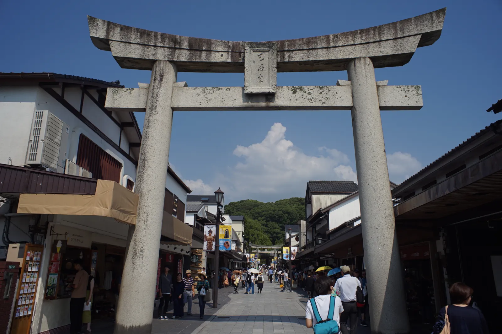 参道入口の石鳥居と、土産物屋が並ぶ賑わう参道