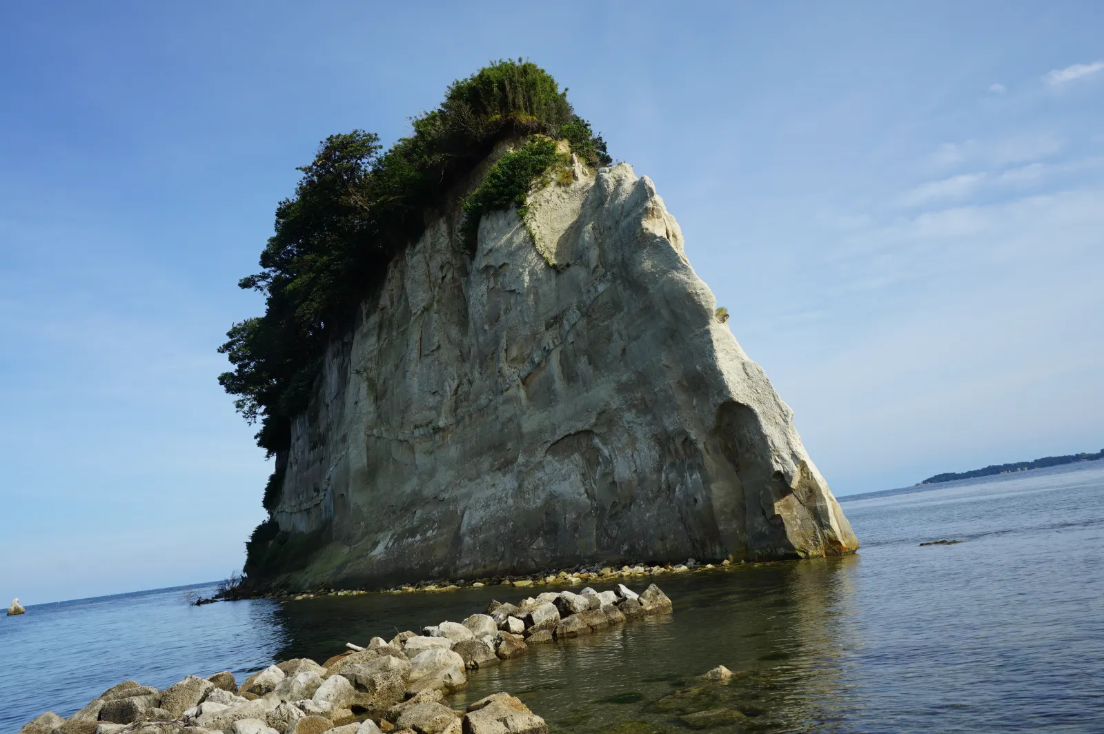 快晴の空の下、海に浮かぶ軍艦のような見附島